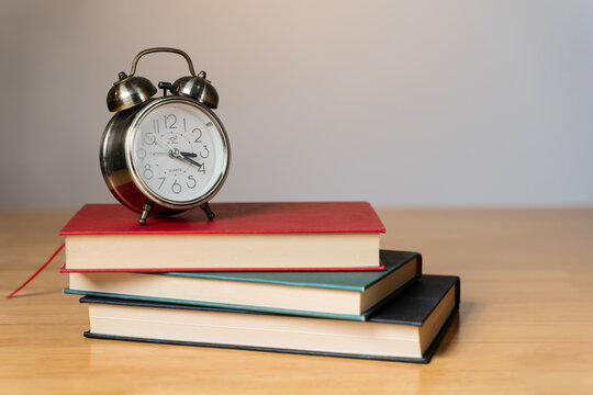 Books and alarm clock on table, education concept