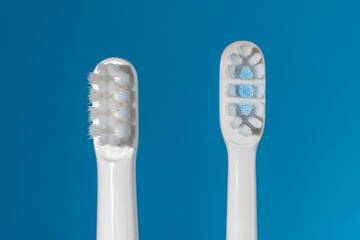 Two white new plastic toothbrush on blue background, closeup