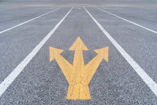Painted and weathered yellow arrows on a street in Funchal. Disruptive ideas in business with three-way.