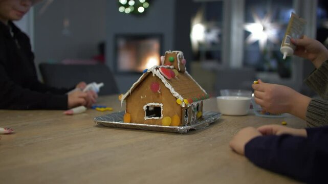 Static view of children preparing ginger bread house with candy at Christmas