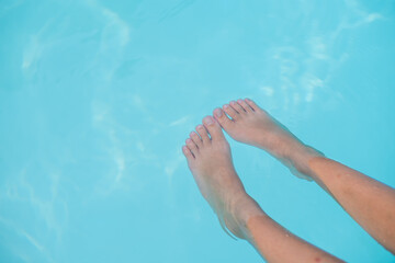 women's legs in blue pool water