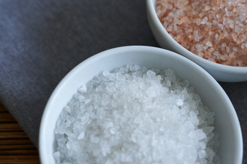 sea salt in a bowl on a wooden background, top view.