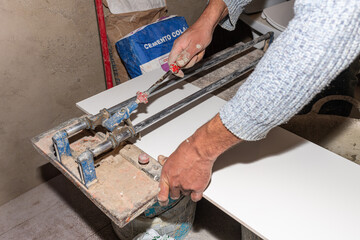 Construction worker cutting ceramic tiles using a manual tile cutter during renovation work