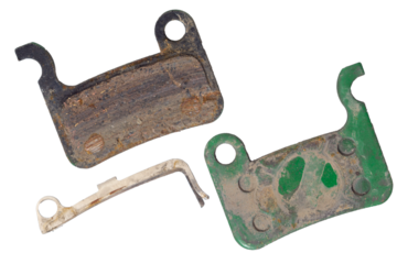 Isolated worn dirty bicycle brake pads with cotter pin on white background