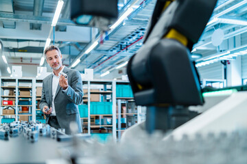 Man in a production hall with industrial robot in a business setting