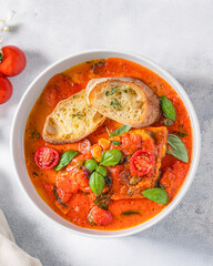Top-down view of a bowl of lasagna soup with rich tomato broth, cherry tomatoes, fresh basil, and crispy toasted bread. A warm and comforting Italian-inspired dish, served on a light textured