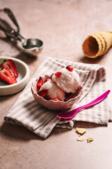 Erdbeereis Kugel in einer Schüssel auf einer gestreiften Stoffserviette. Sommer, Dessert. 