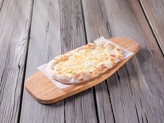 pizza 4 cheese on a wooden board cooked in a wood stove.Centered composition .Top view.