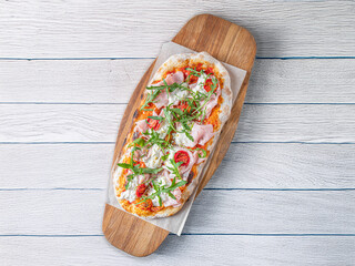 Italian pizza with mozzarely and dilapidated muzzle with a pistachio on a wooden board. 