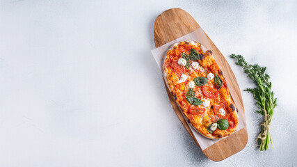 Classic Margherita pizza with a thin, crispy crust, rich tomato sauce, melted mozzarella, and fresh basil leaves. Served on a rustic wooden board with a warm, textured background, emphasizing its