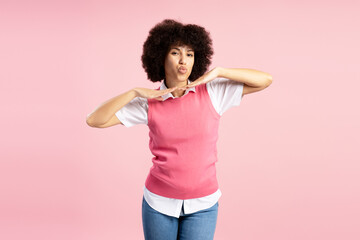 Playful young Latin woman sending a kiss on pink background