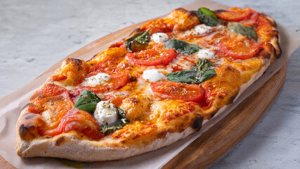 Classic Margherita pizza with a thin, crispy crust, rich tomato sauce, melted mozzarella, and fresh basil leaves. Served on a rustic wooden board with a warm, textured background, emphasizing its