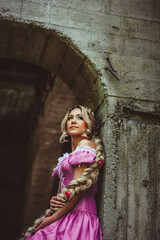 Beautiful girl with long hair braided in a braid, in corset and magnificent pink dress.