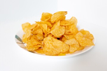 A pile of puffed potato chips snacks on a white painted plate
