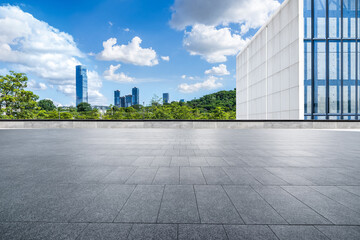 Fototapeta premium Empty square floor and modern buildings with cityscape under blue sky