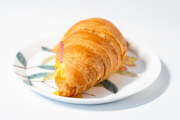A beef and cheese croissant on a Chinese white painted plate, white background