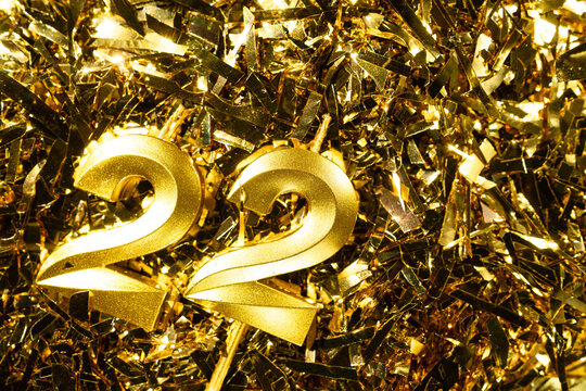 Number 22 golden candle for celebration birthday on festive tinsel background. Twenty-second year birthday. Concept of celebrating birthday