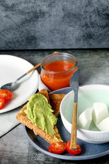 Still life of fresh cheese with gazpacho and avocado toast