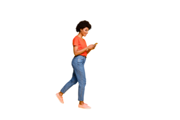 Side profile photo of cheerful cute attractive young influencer browsing through her telephone wearing jeans denim orange t-shirt sneakers isolated over vibrant color background