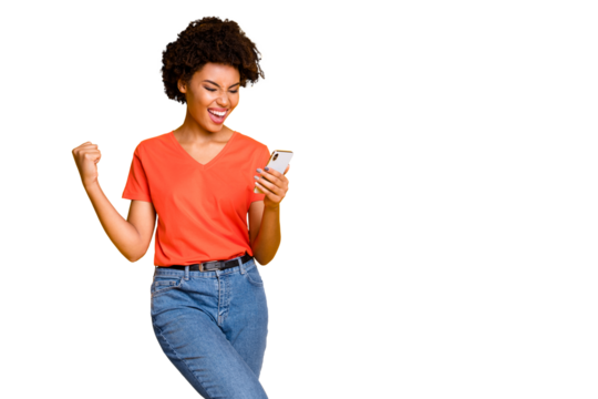 Copyspace photo of fashionable stylish trendy cheerful champion curly wavy having received feedback looking at phone screen wearing jeans denim orange t-shirt isolated yellow vivid color background