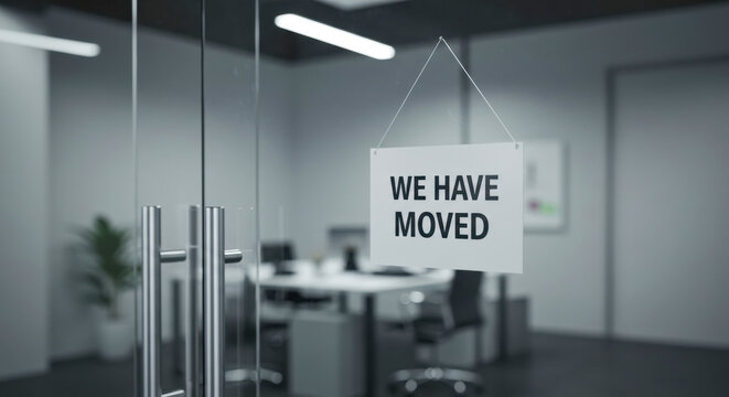 Office relocation announcement with a sign indicating the new location in a modern workspace setting