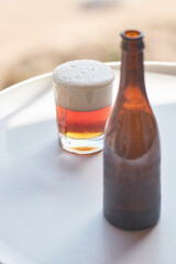 Bottle and glass of beer on circle table. Shallow depth of field. Focus on a glass.