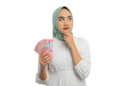 Pensive young Asian woman in green hijab and white blouse touching his chin, holding money, looking up with doubtful expression isolated on transparent background