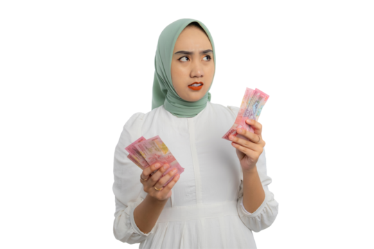 Pensive young Asian woman in green hijab and white blouse holding bunch of money and looking up with doubtful expression isolated on transparent background