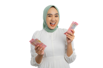Excited young Asian woman in green hijab and white blouse holding lots of cash banknotes with happy expression isolated on transparent background