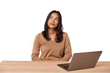 Filipino woman at desk with laptop dreaming of achieving goals and purposes