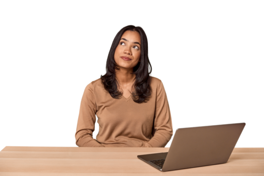Filipino woman at desk with laptop dreaming of achieving goals and purposes