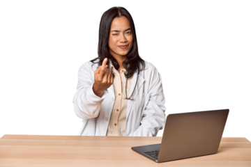 Young Filipino doctor with laptop in studio pointing with finger at you as if inviting come closer.