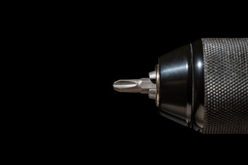 Chuck for cordless screwdriver with bit for unscrewing or screwing screws on black background,...