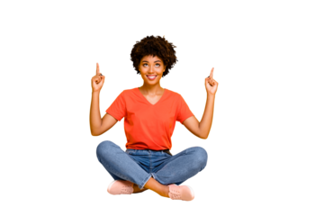 Full length body size photo of charming cute nice attractive gorgeous black girlfriend sitting with her legs crossed on floor pointing up to show something isolated yellow bright color background