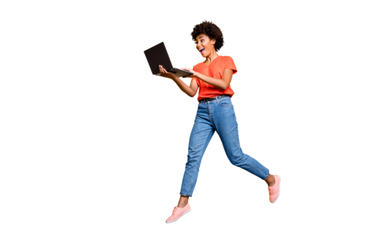 Full length photo of excited funny funky curly hair girl use her laptop find news information about sales jump wear denim jeans stylish trendy sneakers t-shirt isolated over yellow color background