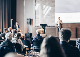 Speaker giving a talk in conference hall at business event. Rear view of unrecognizable people in...