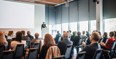 Speaker giving a talk in conference hall at business event. Rear view of unrecognizable people in audience at the conference hall. Business and entrepreneurship concept