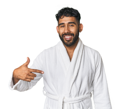 Hispanic male in a robe in studio person pointing by hand to a shirt copy space, proud and confident - Powered by Adobe