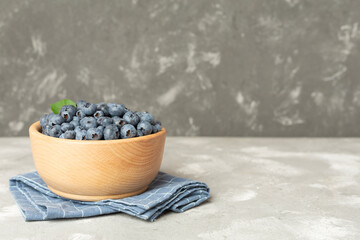 Bowl with fresh blueberries on concrete background