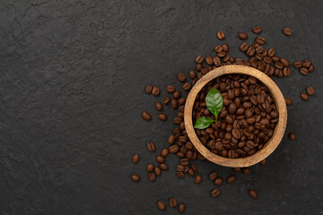 Roasted coffee beans with leaves on concrete background,top view