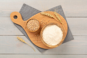 Bowl with spelt flour on wooden background, top view