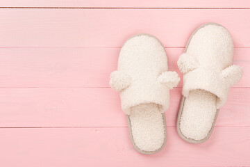 Soft teddy slippers on wooden background, top view