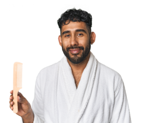Young Hispanic man with robe holding a comb in studio