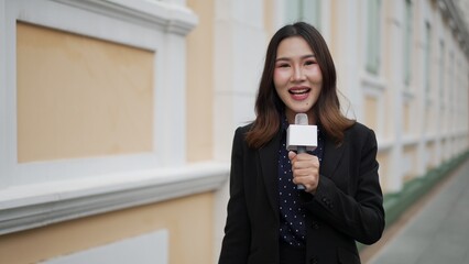 woman reporter smiling with microphone during live news report outdoors