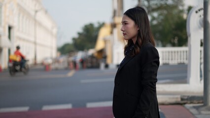 asian female reporter in side view standing on city street with serious and focused expression