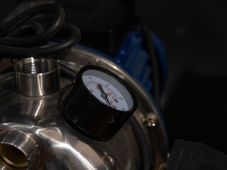 A black and silver water pressure gauge sits on a silver pipe