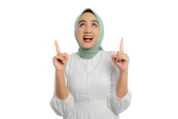 Happy young Asian woman in green hijab and white blouse pointing finger up with both hands, showing copy space for advertising isolated on transparent background