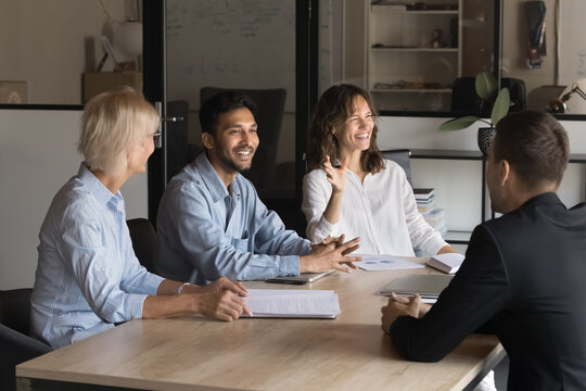 Happy diverse business people communicating at professional business meeting, negotiating and laughing. Executive board team leader friendly discussing work with manager people in office coworking