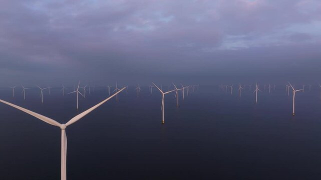 Offshore turbines powering sustainable future along Dutch waters. Aerial drone video