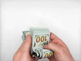 Man holding 100 dollar bills in closed folded position and counting them with both hands on white...
